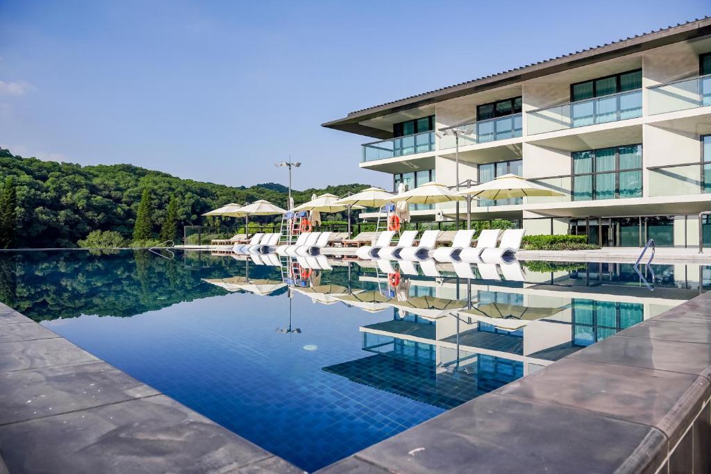 ein Hotel mit einem Pool mit Stühlen und Sonnenschirmen in der Unterkunft Oriental Resort Guangzhou in Guangzhou