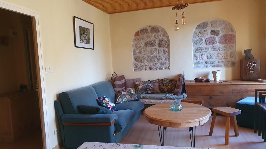 salon z niebieską kanapą i stołem w obiekcie Gîte à la campagne 3 * proche A75 en Margeride. w mieście La Roche