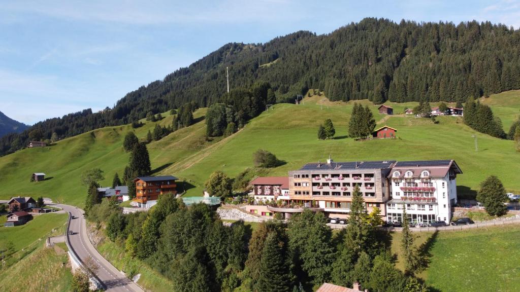 a hotel in the mountains with a green hill at Familotel Alphotel in Hirschegg