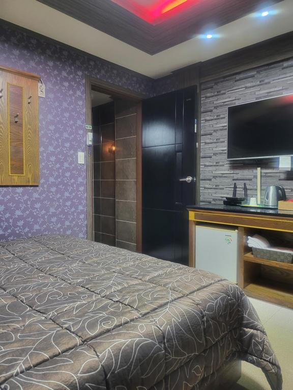 a hotel room with a bed and a flat screen tv at Gohyeon Ace motel in Geoje 