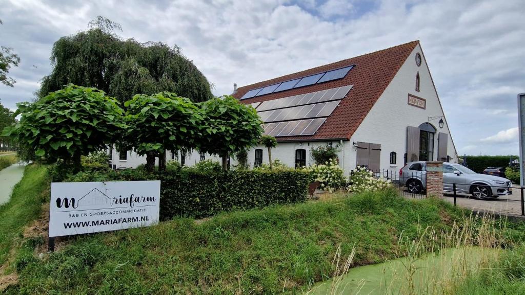 a white building with a sign in front of it at Mariafarm in Zevenbergen