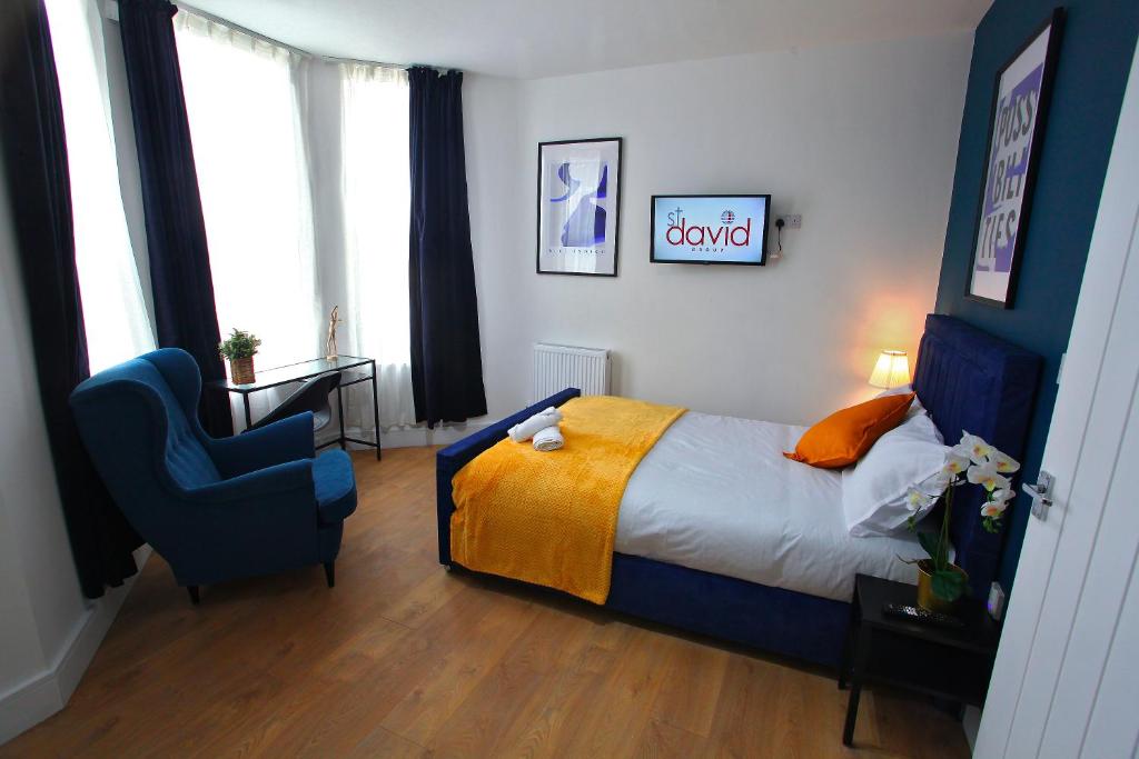 1 dormitorio con 1 cama y 1 silla azul en St David, en Barrow-in-Furness
