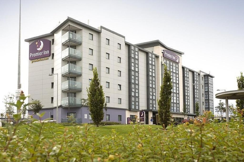 un gran edificio blanco con árboles delante de él en Premier Inn Dublin Airport, en Swords