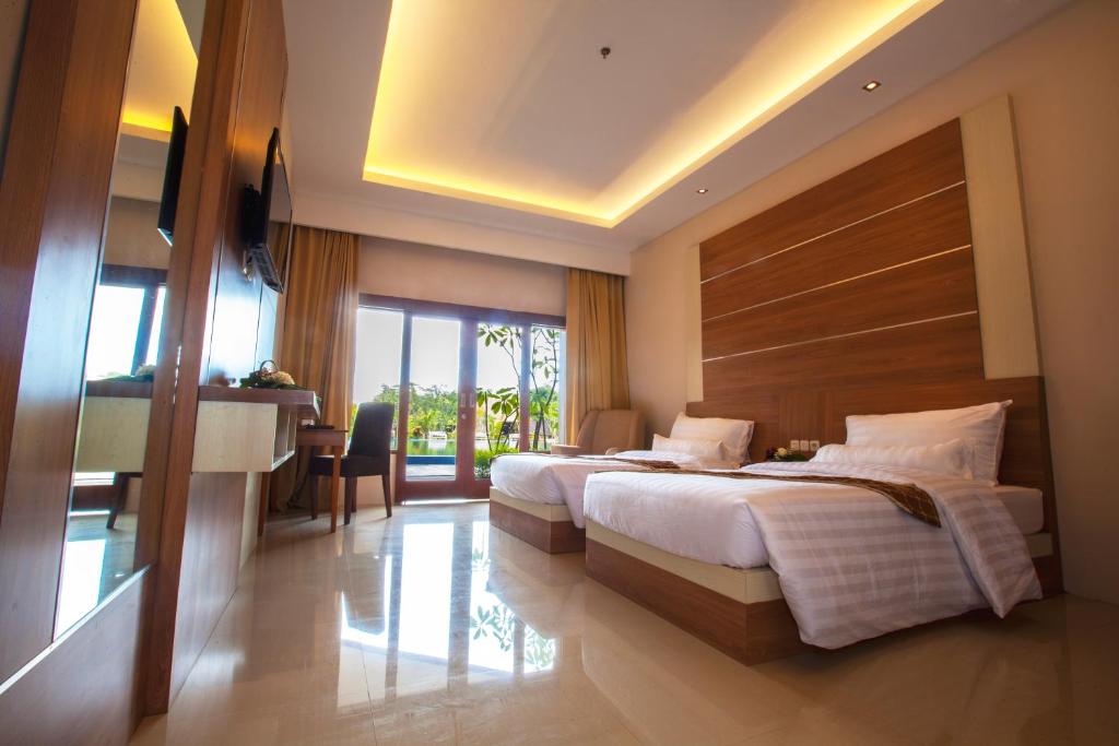 a hotel room with two beds and a table and a desk at GRAND MULYA HOTEL BOGOR in Sukaraja