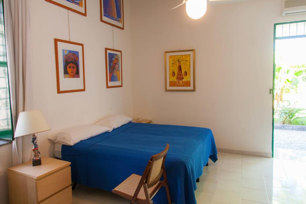 una camera con un letto blu e una sedia di La Casa Nel Parco a SantʼAgata di Militello
