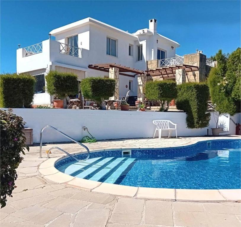 a villa with a swimming pool in front of a house at Sunset Boutique Guest House in Paphos City