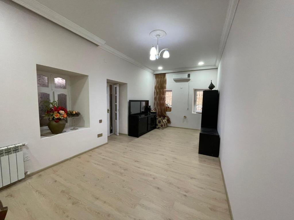 una sala de estar vacía con paredes blancas y suelo de madera. en Holiday House en Bakú