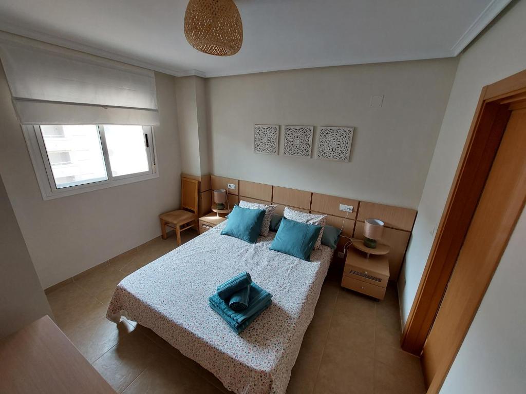 1 dormitorio con 1 cama grande con almohadas azules en Apartamento Neptuno Sunrise Magic World, en Oropesa del Mar