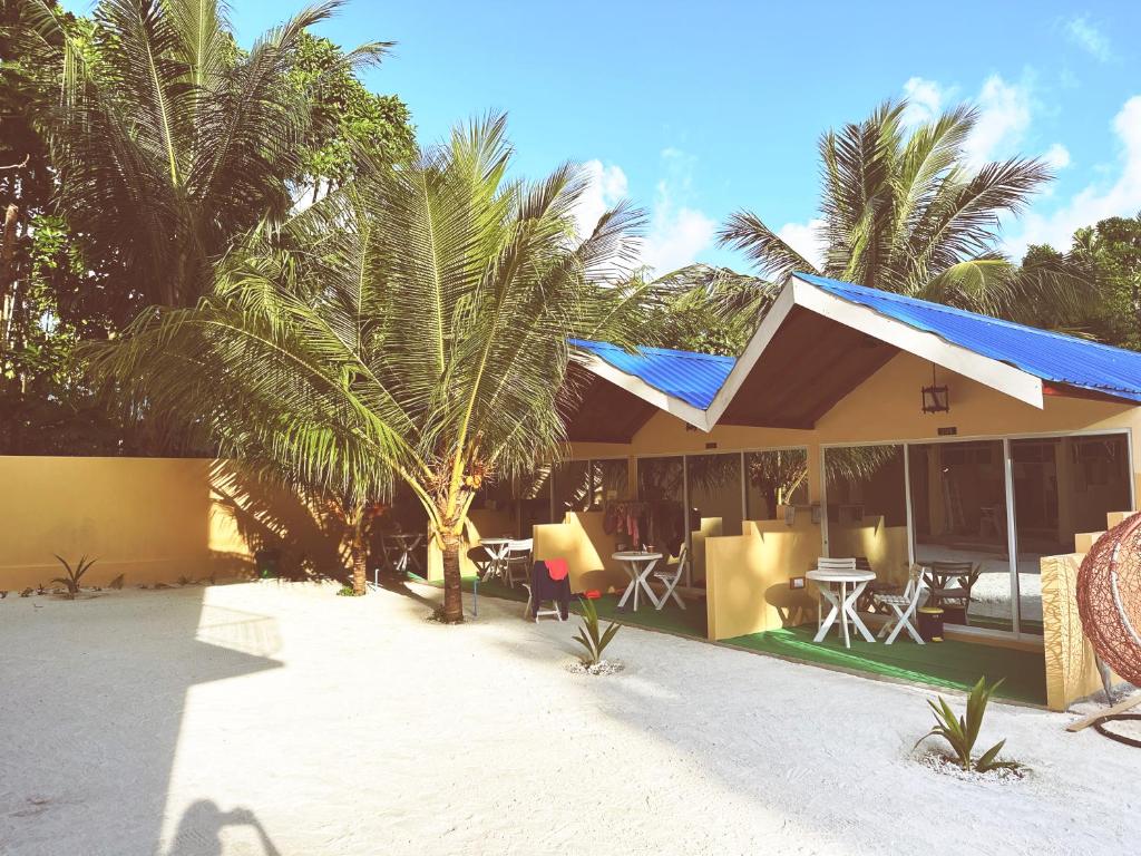 a house with a blue roof and palm trees at Relax Lodge in Thoddoo