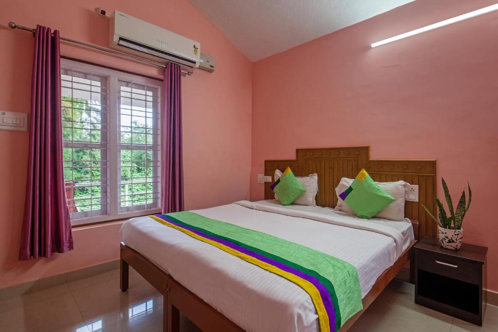 a bedroom with a large bed with pink walls at Treebo Trend Yajna Comforts in Madikeri