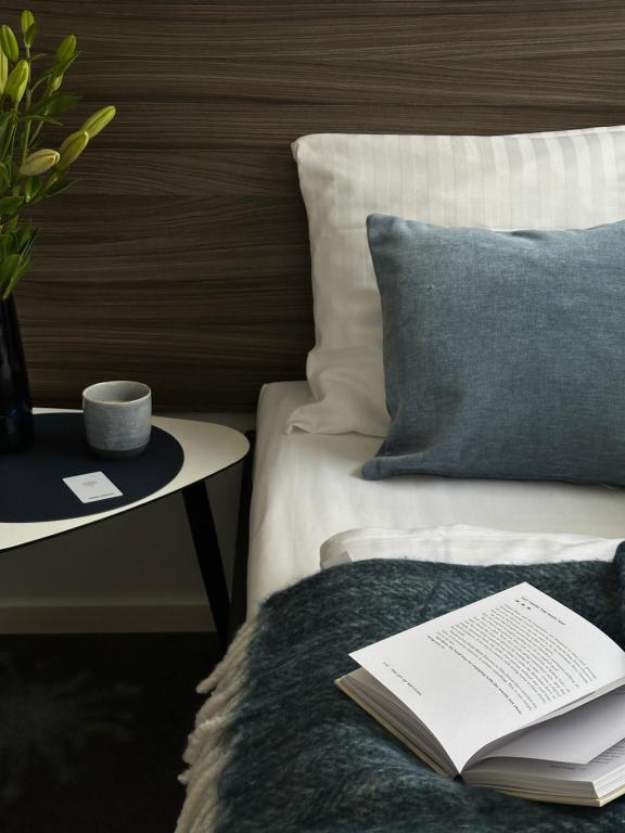 a book on a bed with a table with a cup on it at ApartHotel Faber in Aarhus