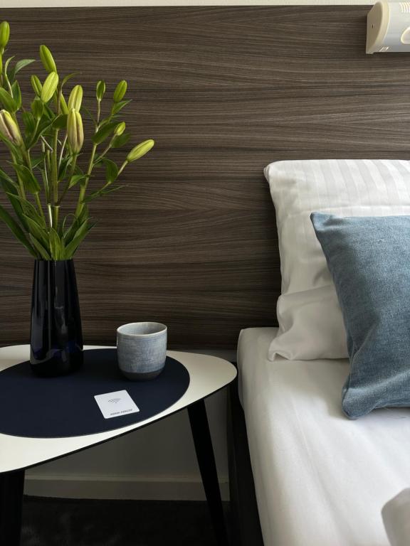 a black vase with a plant on a table next to a bed at ApartHotel Faber in Aarhus