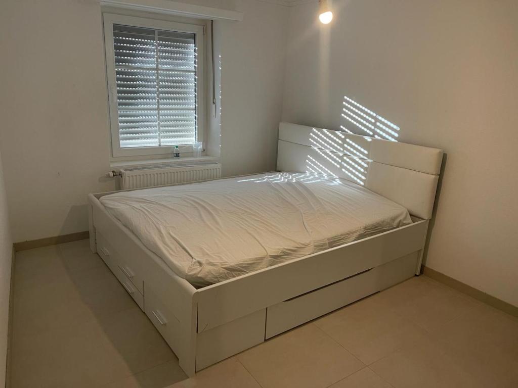 a bedroom with a large bed with a window at Maison in Dudelange