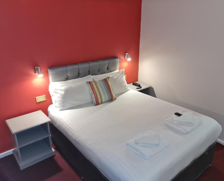a bedroom with a white bed with a red wall at Superior Hotel in Dudley