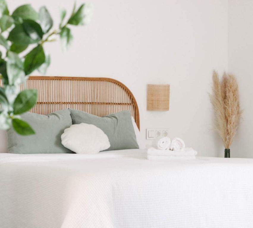a bed with white sheets and pillows on it at Apartamento Pemedal in Villaverde