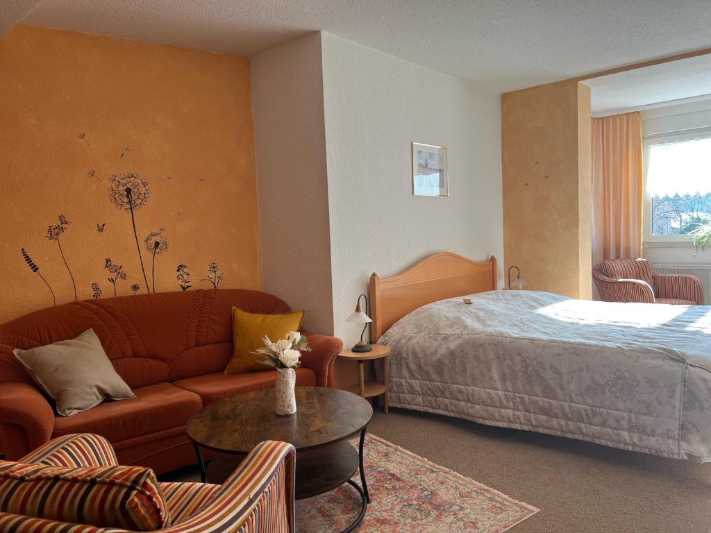 クヴェードリンブルクにあるLandhaus Pusteblumeのベッド、ソファ、テーブルが備わるホテルルームです。