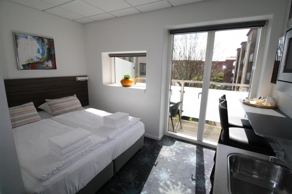 a bedroom with a bed and a desk and a window at ApartHotel Faber in Aarhus