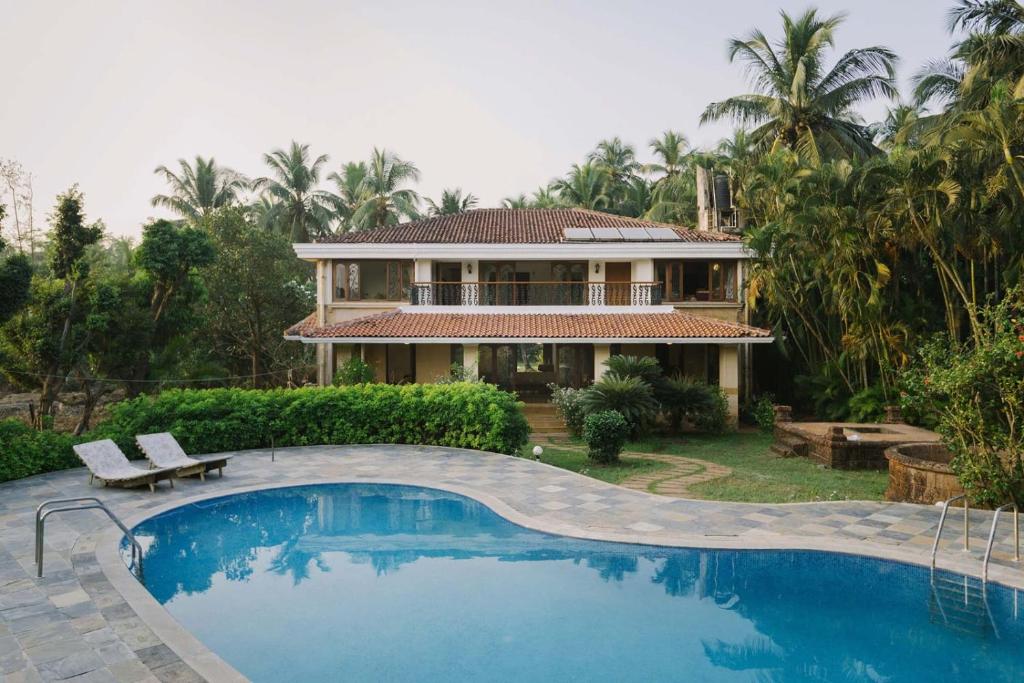a house with a swimming pool in front of a house at Theta Villa in Alibag