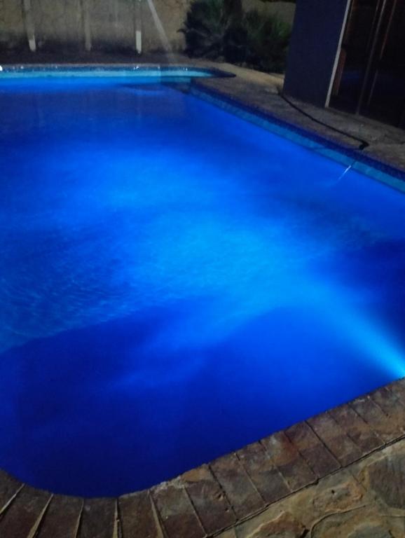 a blue swimming pool at night at Van Dyk guest house in Boksburg