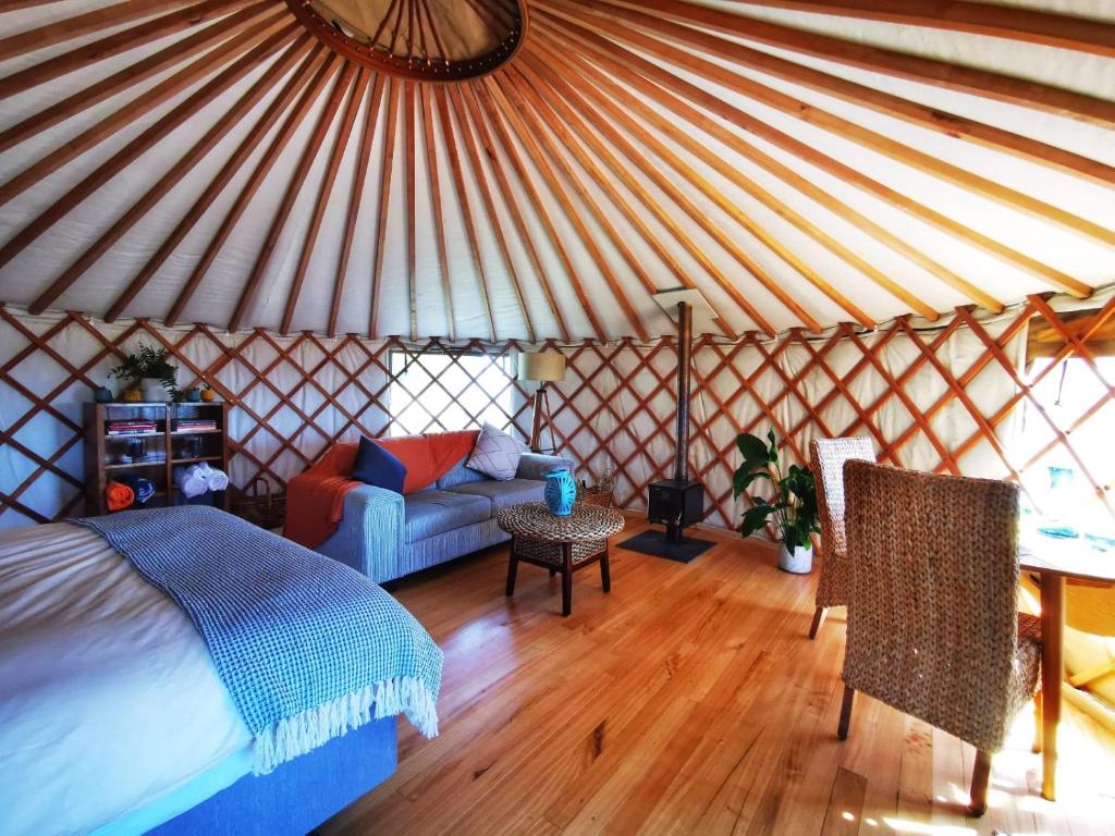 - une chambre avec un lit et un canapé dans une yourte dans l'établissement Petal Creek Farm, à Tarakohe