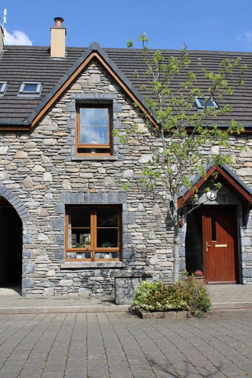 a stone building with two windows and a door at Cosy Holidayhomes Kerry in Kenmare