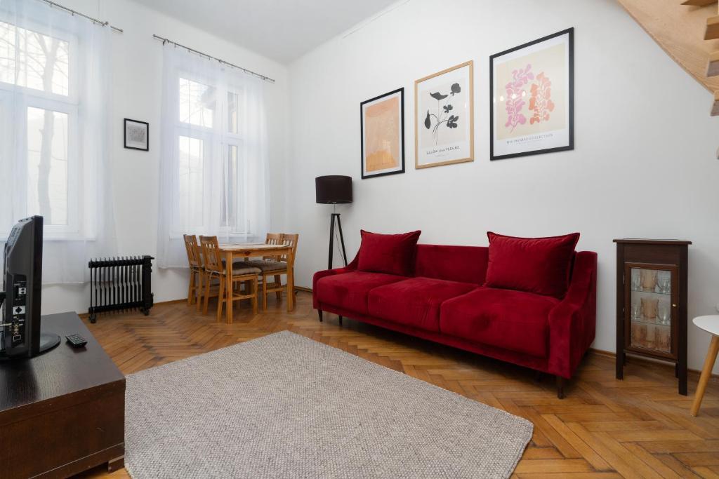 uma sala de estar com um sofá vermelho e uma mesa em Park Strzelecki Two-Level Apartment em Cracóvia