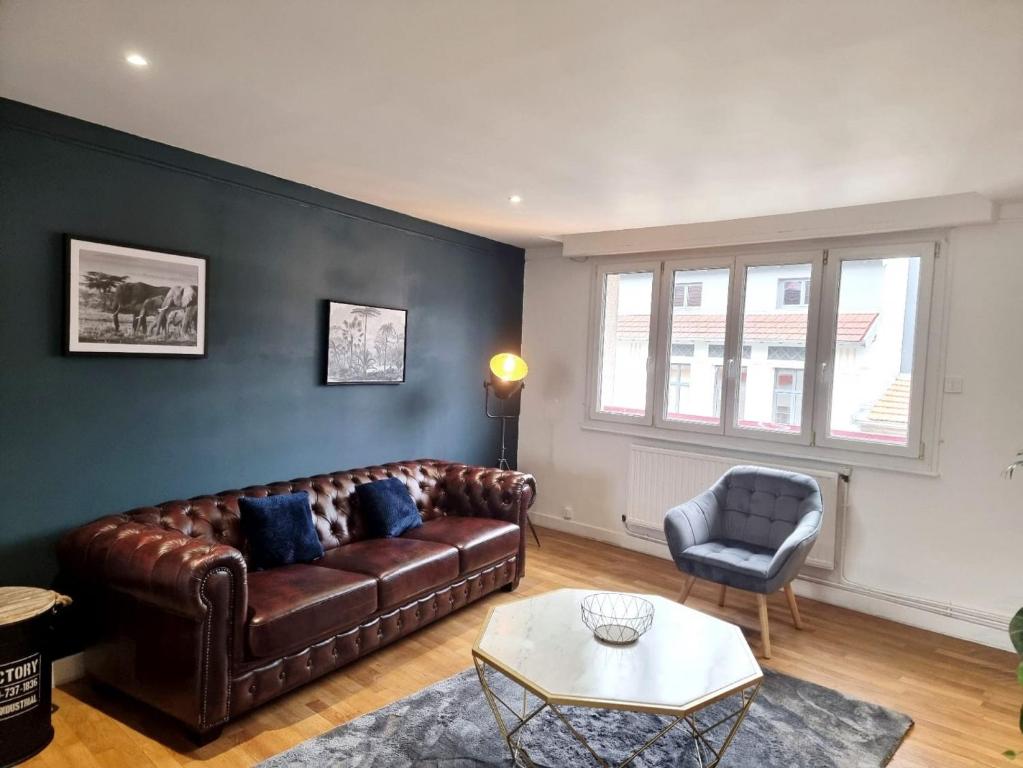 - un salon avec un canapé en cuir et une chaise dans l'établissement Le chesterfield - coeur de ville, à Épinal