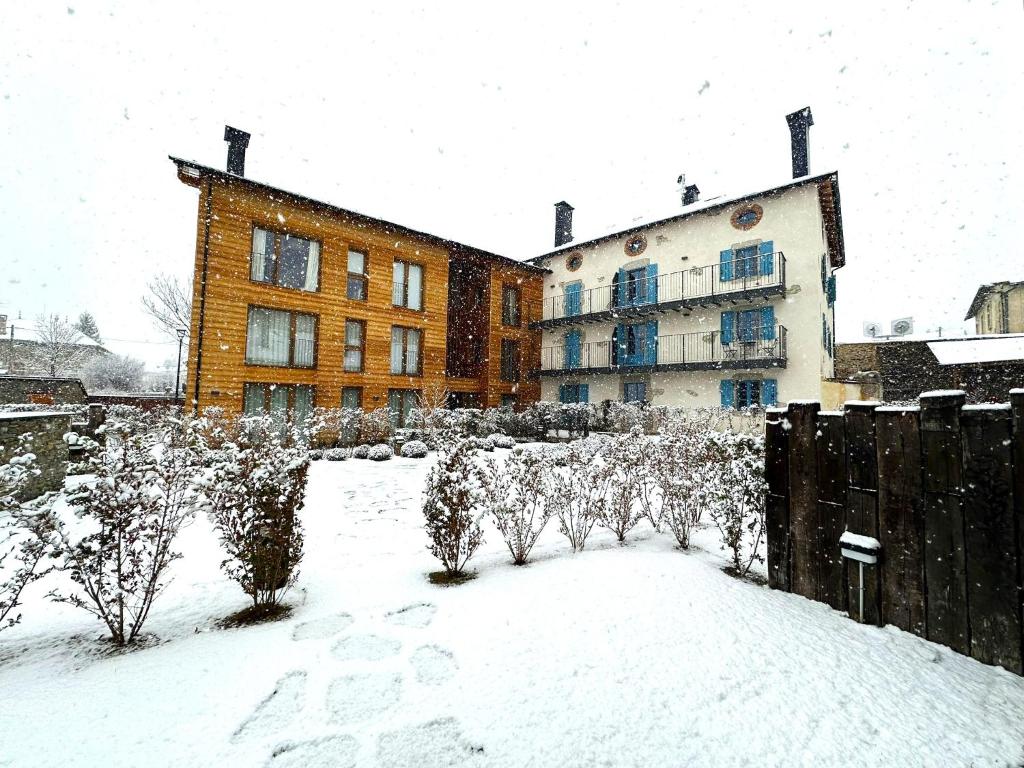 un patio cubierto de nieve con un edificio y árboles en Apartamento con Wifi en Ossèja en Osséja