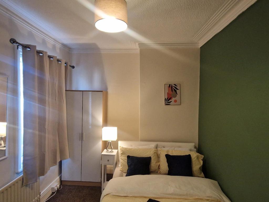 ein Schlafzimmer mit einem Bett mit einer grünen Wand in der Unterkunft Executive 2-Bedroom House in Wallsend in Wallsend