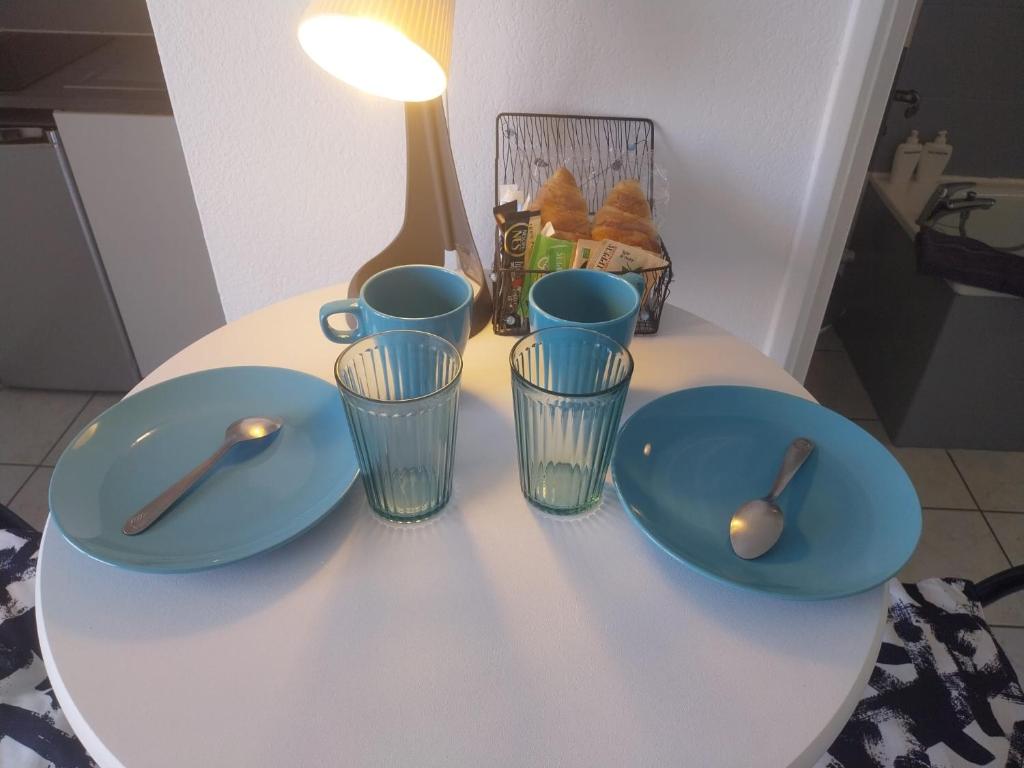 a table with two blue plates and two spoons at Studio dans résidence avec piscine in Montpellier