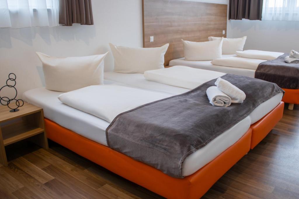 duas camas num quarto de hotel com almofadas em Orange Hotel und Apartments em Neu-Ulm