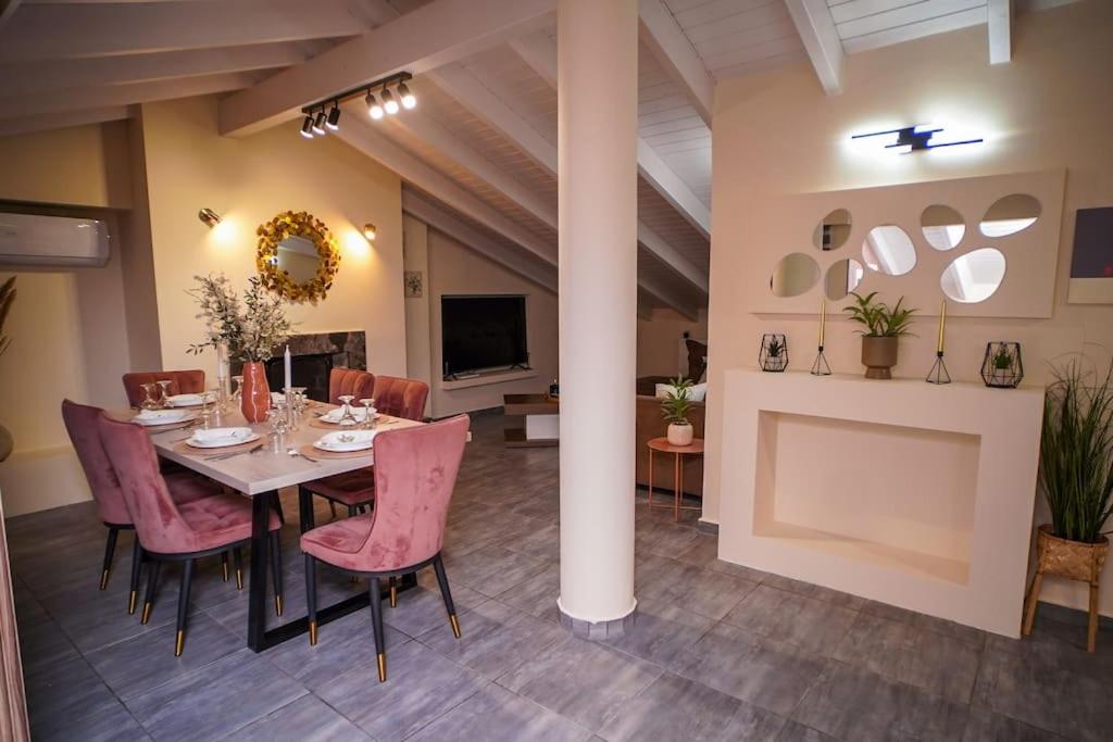 Virós的住宿－Melina's Bright Apartment, Viros Corfu，一间带桌子和粉红色椅子的用餐室
