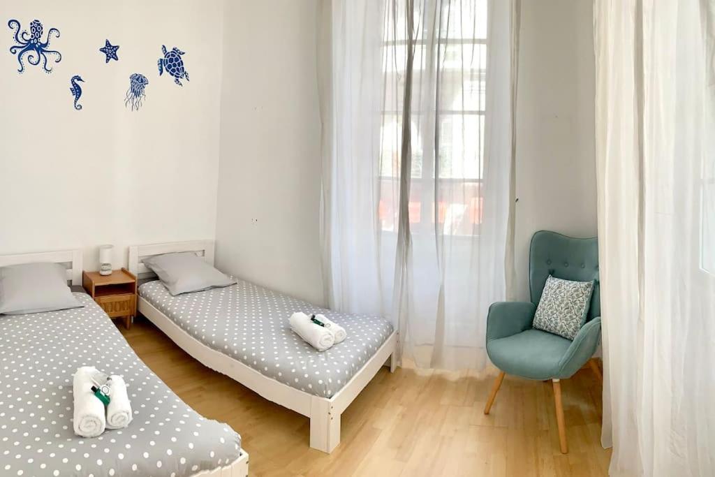 a bedroom with two beds and a blue chair at T3 Terrasse près de la plage in Nice