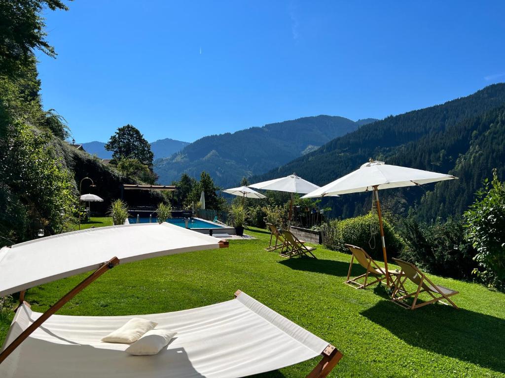 un patio con sillas y sombrillas y una piscina en ALM SEASONS Premium Chalet & Studios, en Saalbach Hinterglemm