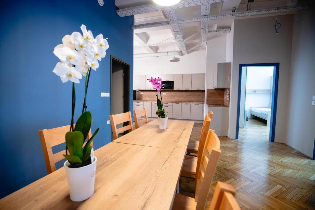 a dining room with a wooden table with white flowers at CafDorm in Maribor