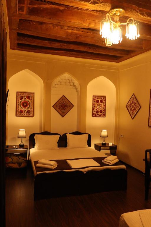 1 dormitorio con 1 cama, 2 lámparas y techo en Al Bukhari Boutique Hotel, en Bukhara