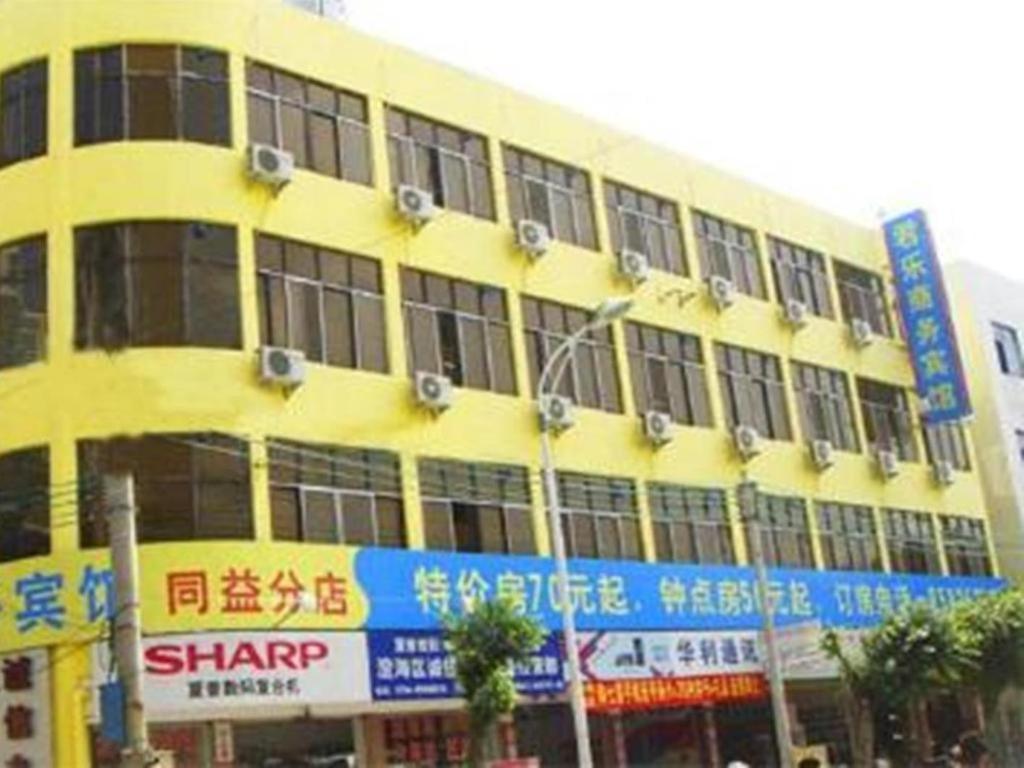 un bâtiment jaune avec des panneaux sur son côté dans l'établissement Shantou Jun Yue Business Hotel Tongyi Road Branch, à Batou