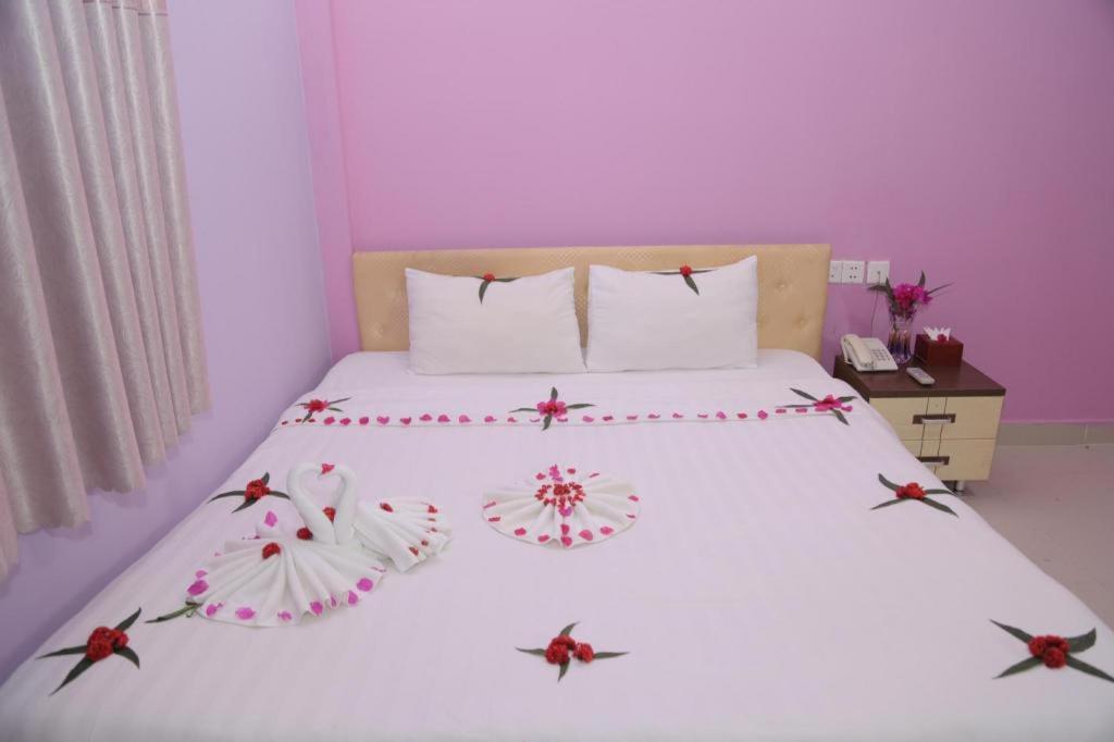 Un dormitorio con una cama blanca con flores. en LUCKY 89 BORDER CASINO en Svay Riĕng
