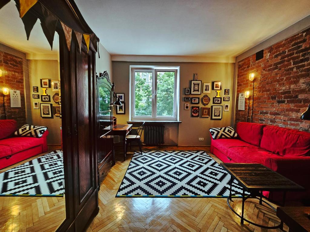 華沙的住宿－Art Murano，客厅设有红色的沙发和砖墙