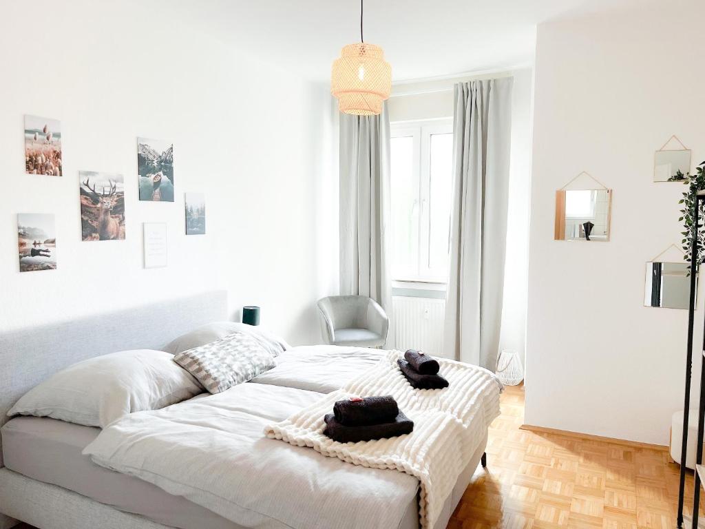 a white bedroom with a bed with towels on it at City Comfort Essen - Wohndomizil mit Balkon, Büro und Netflix in Essen