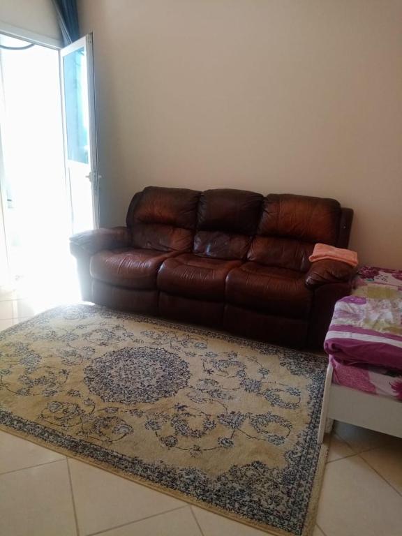 a brown leather couch in a living room with a rug at ORIENT TOWER STUDIO in Ajman 