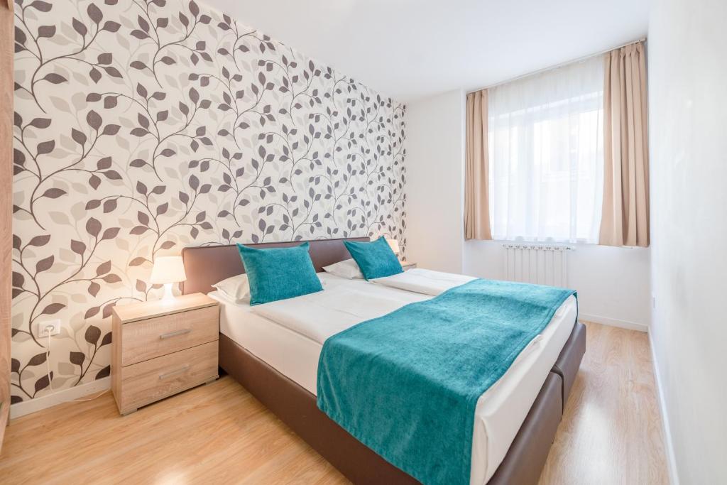 ein Schlafzimmer mit einem Bett mit blauer Bettwäsche und einer Wand in der Unterkunft Prince downtown apartments with free parking in Budapest