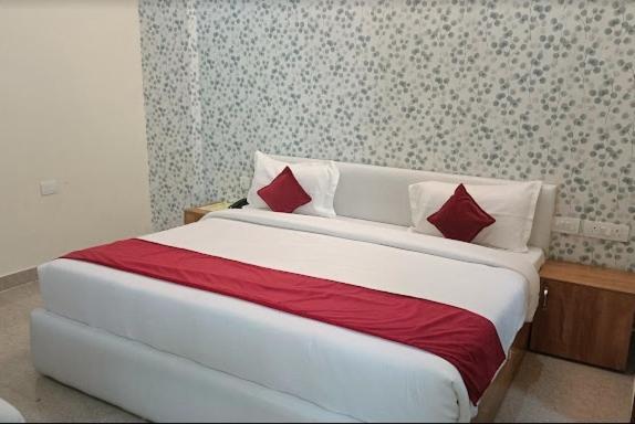 a bedroom with a large bed with red and white pillows at The Purezza in Greater Noida