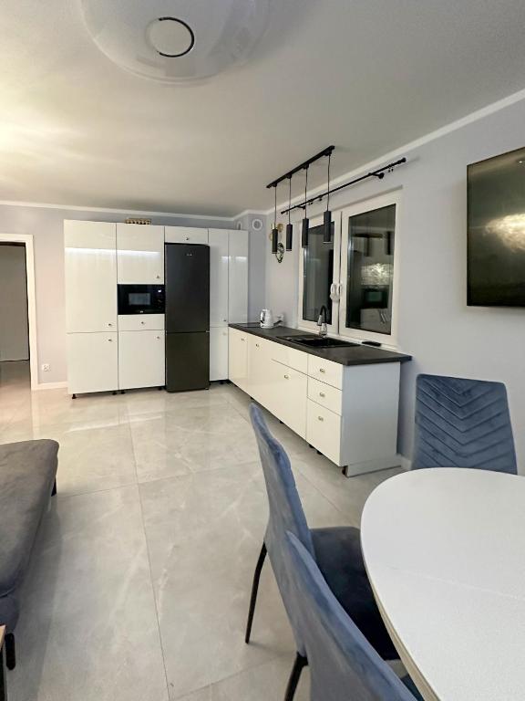 a kitchen with white cabinets and a table and a dining room at PaVoni Apartments Veranda Blu Mare in Łeba