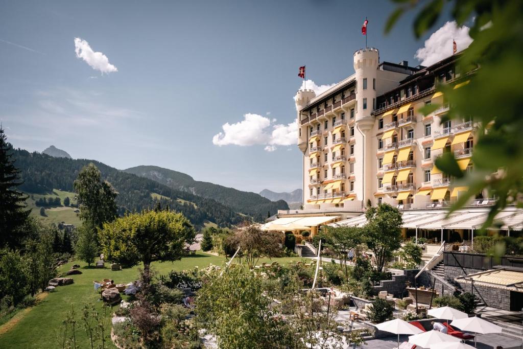 um hotel com um jardim em frente a um edifício em Gstaad Palace em Gstaad