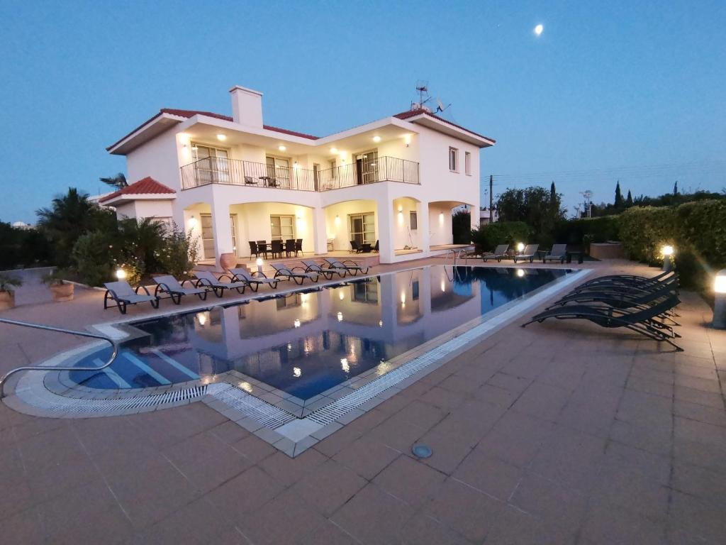 a large house with a swimming pool in front of it at Orchard Blossom Private Villa with Pool in Phrenaros