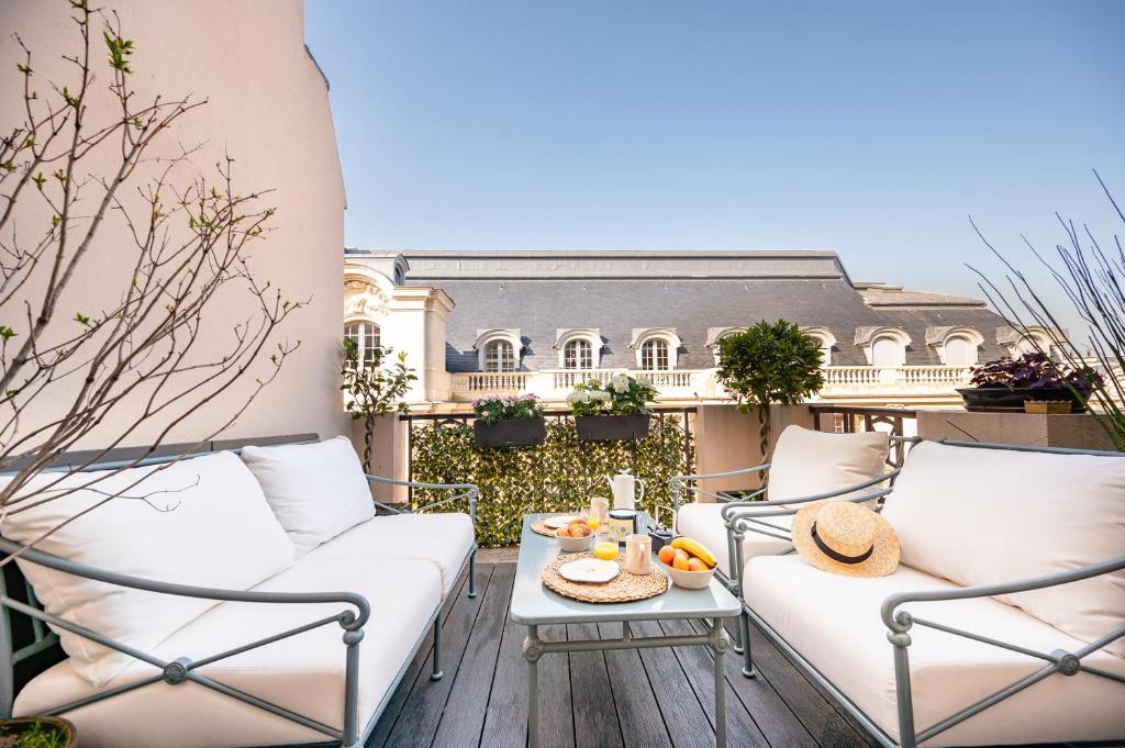 - un balcon avec des canapés blancs et une table avec des fruits dans l'établissement Superb flat with terrasse & 24-7 security in the heart of Paris!, à Paris