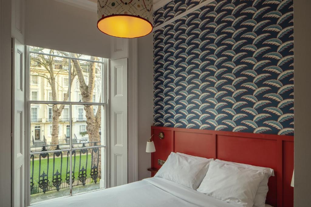 Schlafzimmer mit einem Bett mit einem roten Kopfteil und einem Fenster in der Unterkunft St. David's Hotels Paddington in London