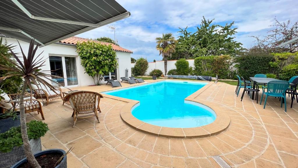 - une piscine avec une terrasse, une table et des chaises dans l'établissement Magnifique Villa avec sa piscine et son billard, à Saint-Martin-de-Ré