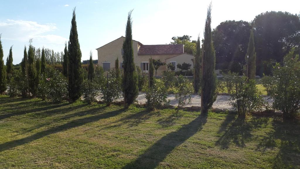 a row of trees in a yard with a house at Le Mas de Guiguite in Mézoargues